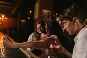 Group of friends taking a selfie together in a busy, noisy bar.