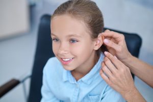 A person with a hearing aid touching their ear, adjusting to the sound of their own voice.