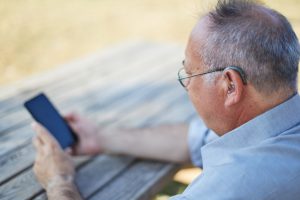 Man using a smartphone to adjust and fine-tune his hearing aid settings.